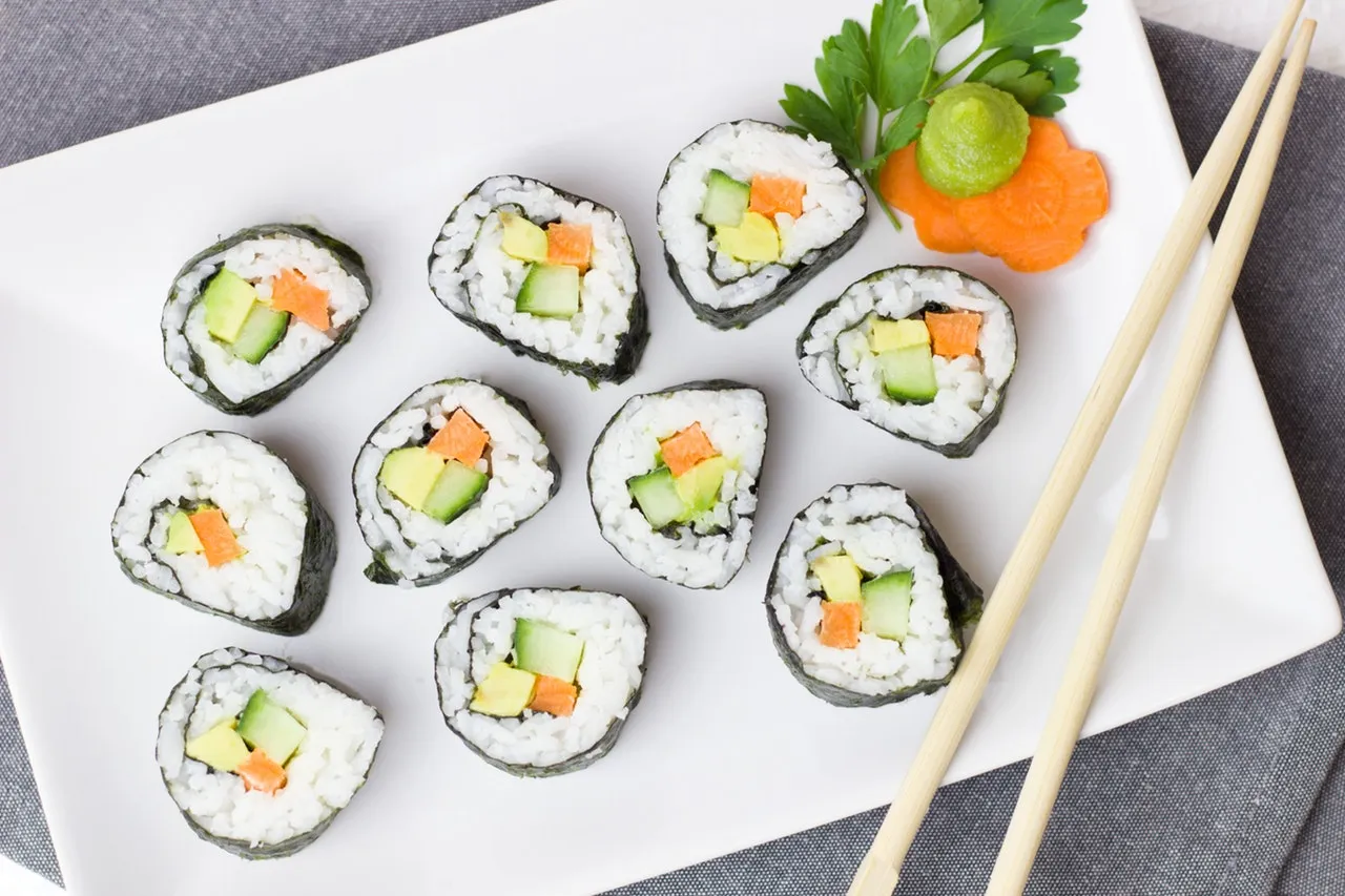 Vegetable maki rolls with chopsticks on a white plate