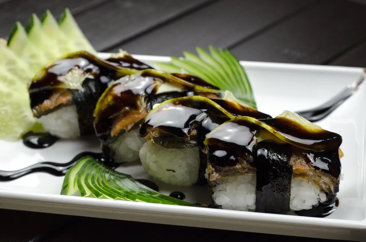 Eel nigiri drizzled with sweet sauce and cucumber garnish