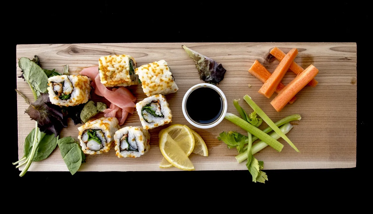 Sushi rolls with ginger, carrot sticks and soy sauce on a wooden board